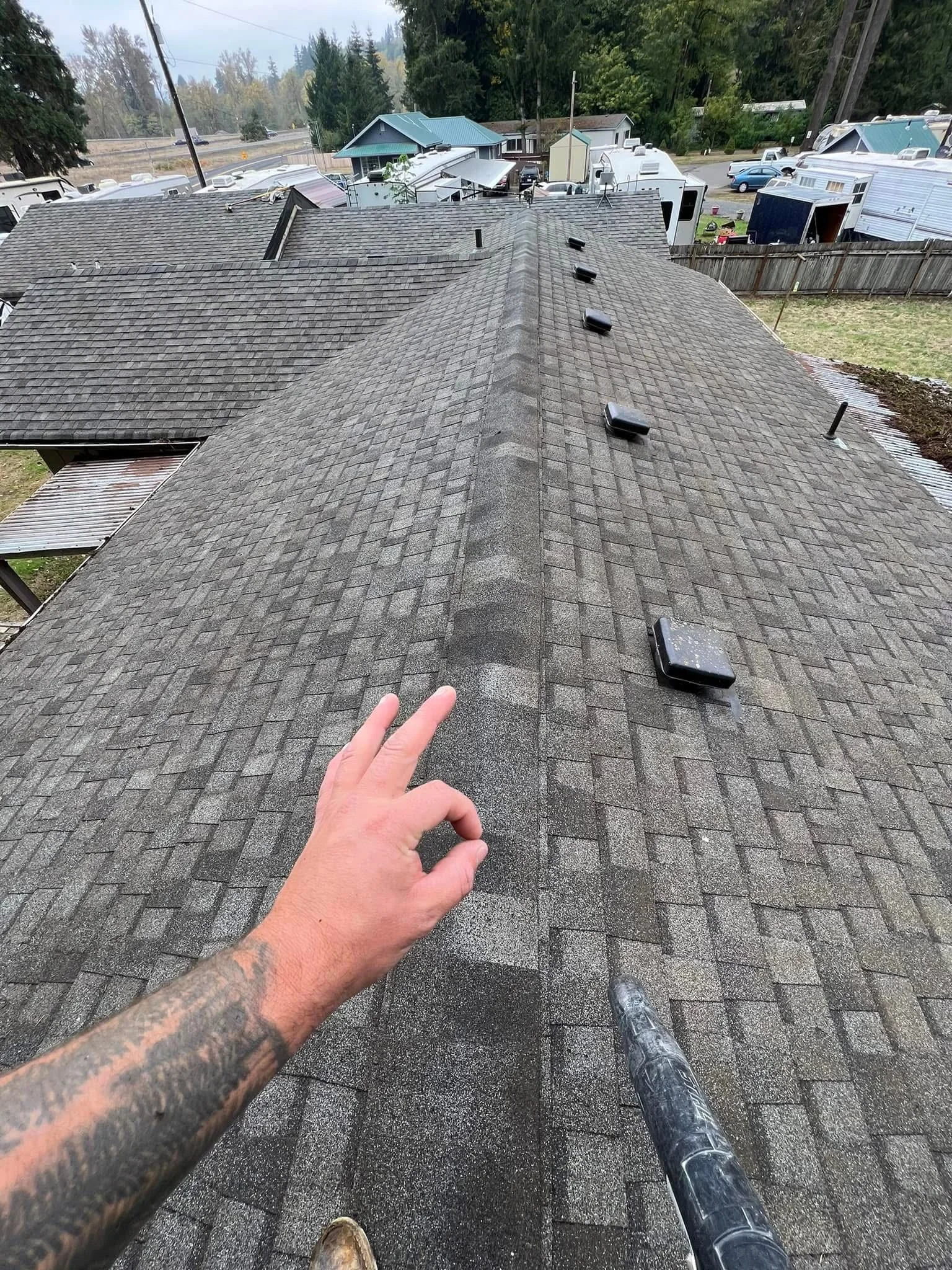 Gray dimensional asphalt shingles installed on residential roof with ridge cap and flashing