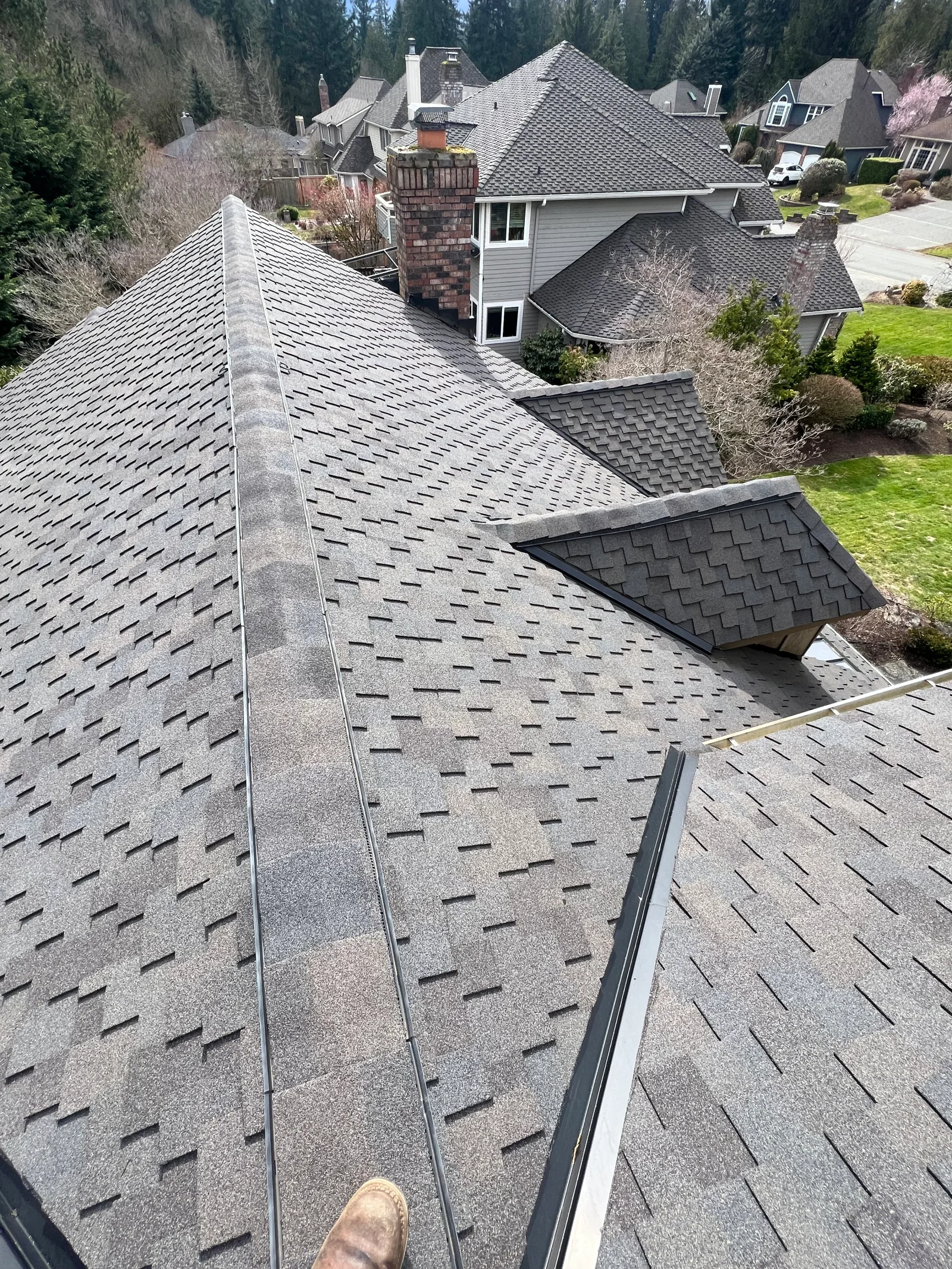 Gray architectural shingles with dimensional pattern on multi-plane residential roof with new gutters