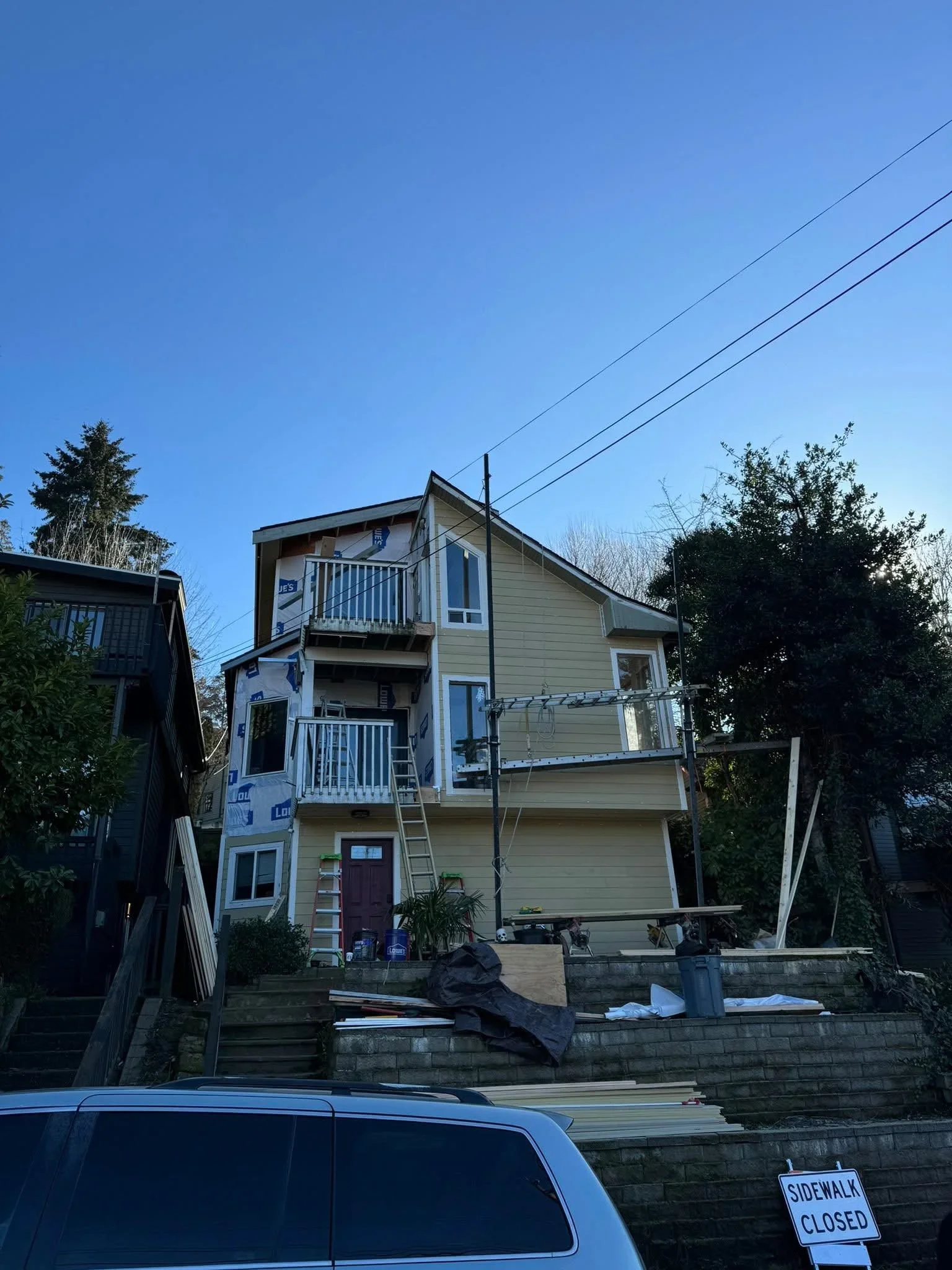 Three-story house with new fiber cement siding, white railings, and deck construction in progress