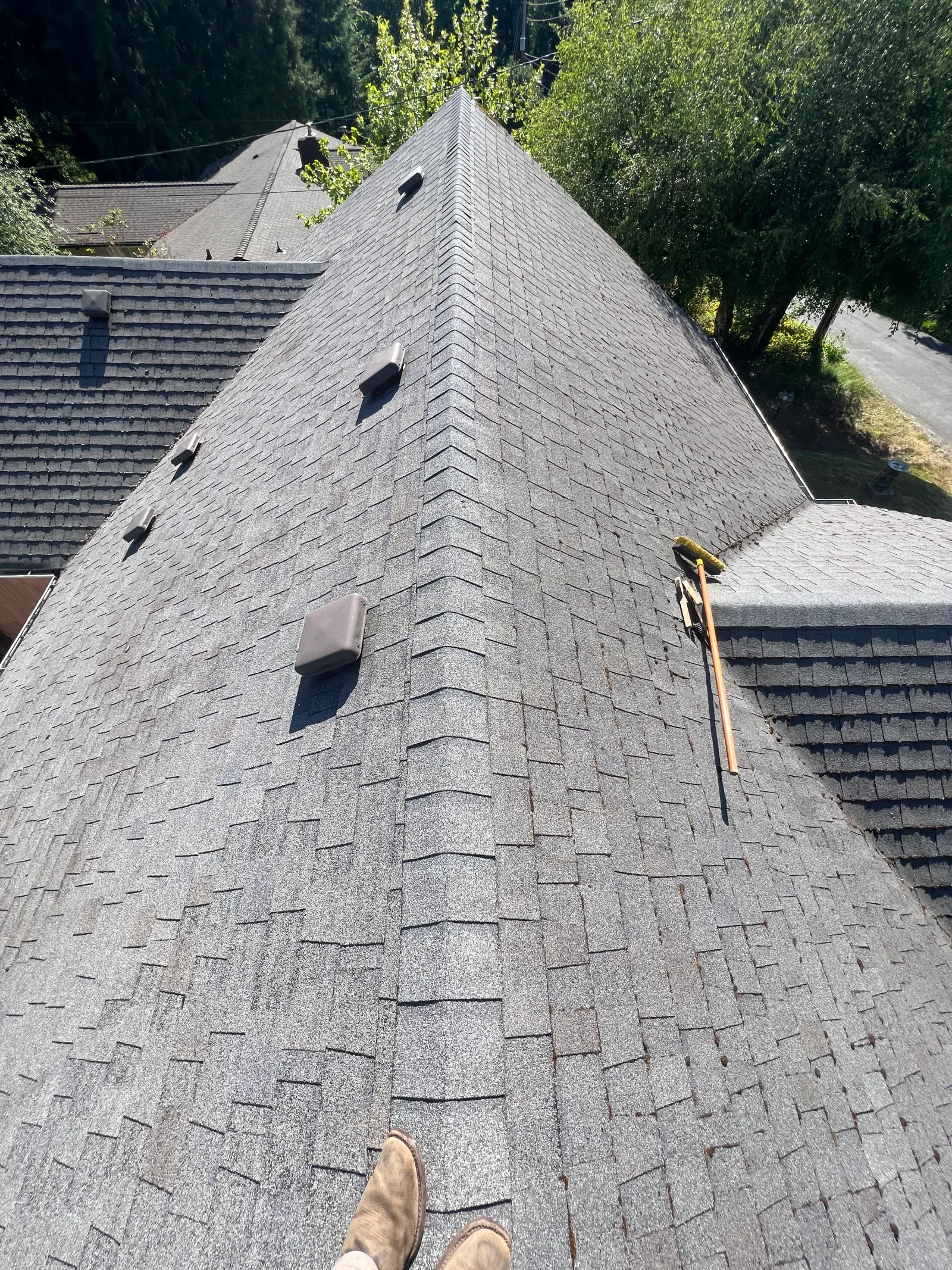 Charcoal gray architectural asphalt shingles installed on peaked tower roof section with multiple planes