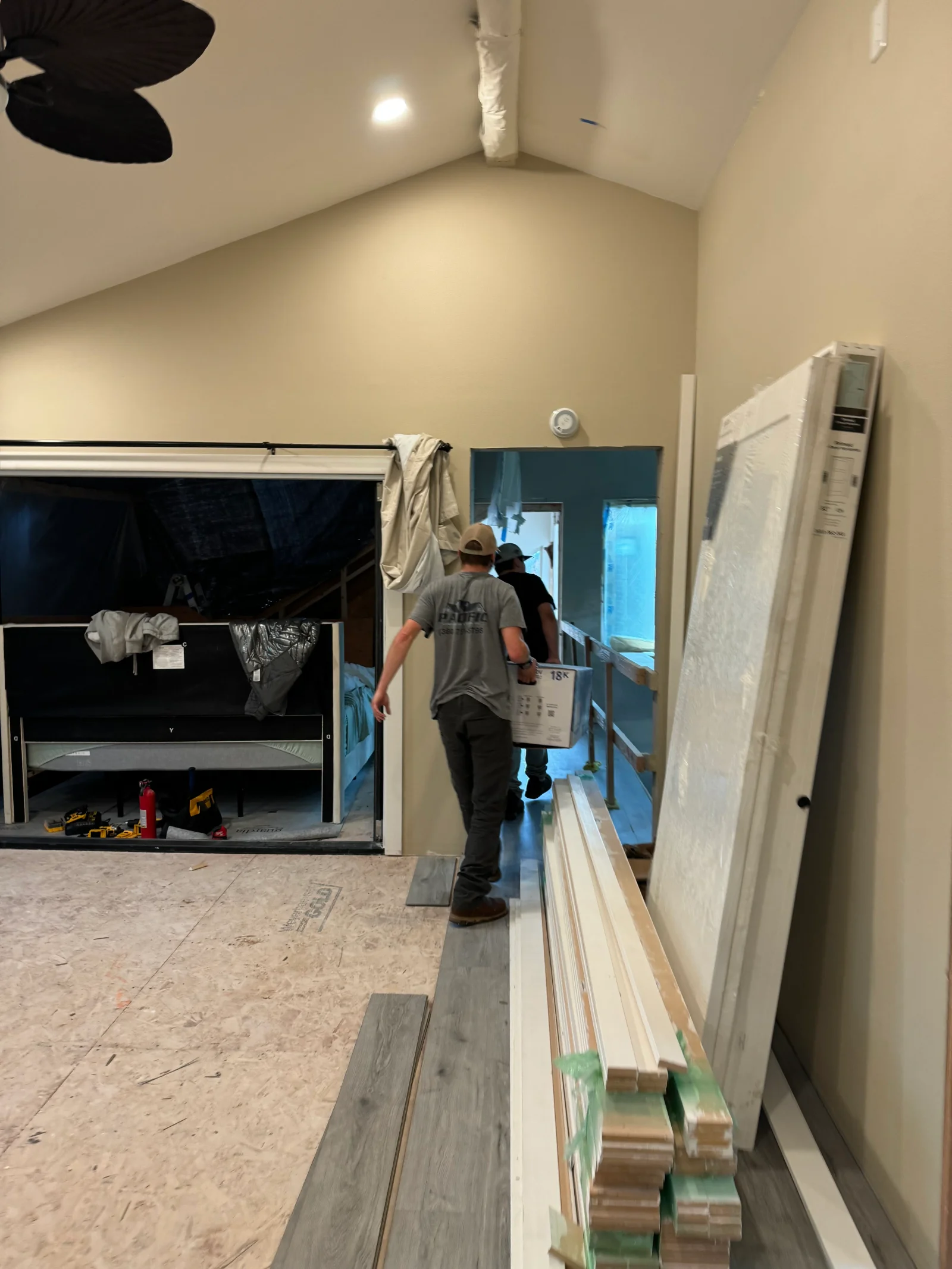 Commercial interior construction with drywall, recessed lighting, and vinyl plank flooring installation in progress