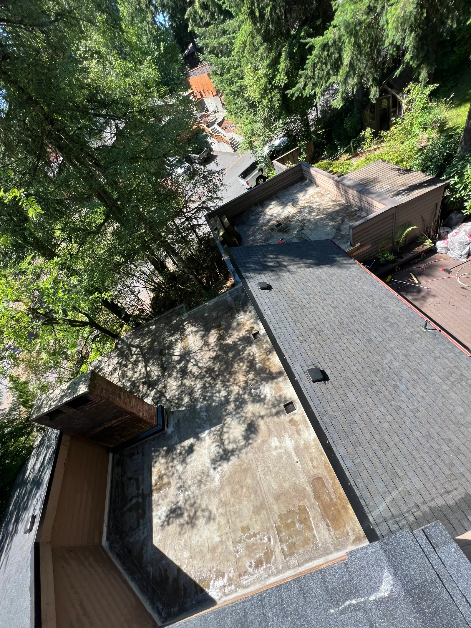 Aerial view of new architectural shingle roof installation with charcoal gray shingles and roof vents