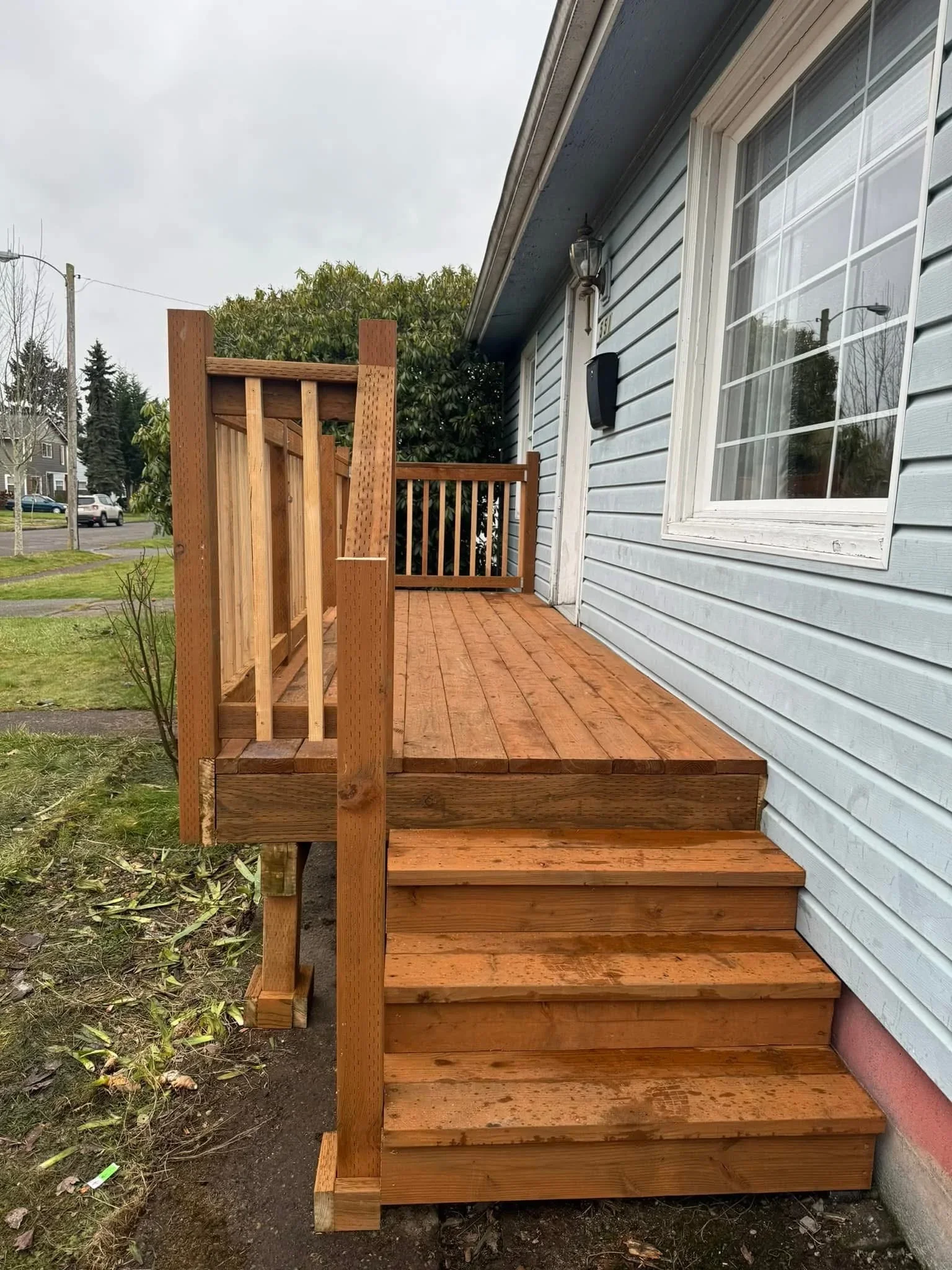 Wooden deck with entry stairs, vertical railing, and pressure-treated decking boards