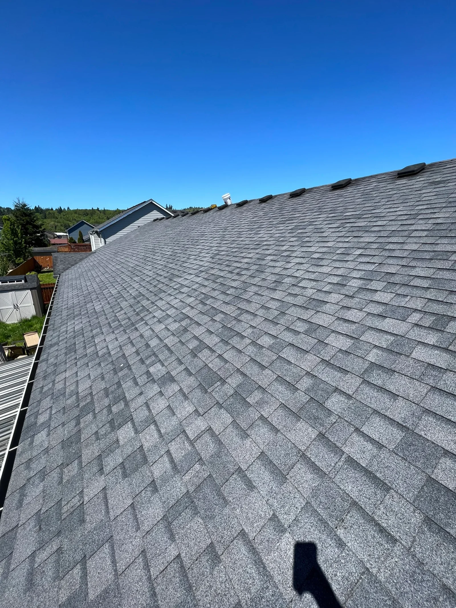 Gray architectural asphalt shingles installed on residential roof with multiple peaks and valleys